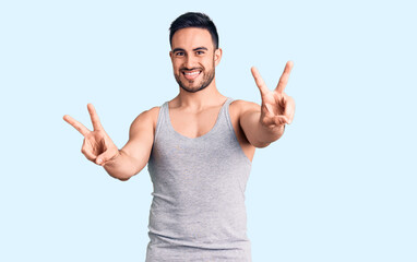 Young handsome man wearing swimwear and sleeveless t-shirt smiling with tongue out showing fingers...