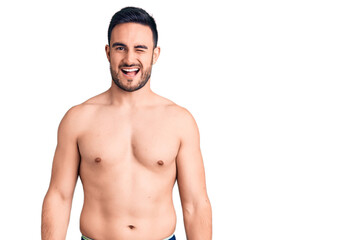 Fototapeta premium Young handsome man wearing swimwear winking looking at the camera with sexy expression, cheerful and happy face.