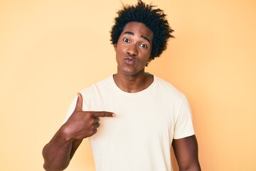 Handsome african american man with afro hair pointing with fingers to himself looking at the camera blowing a kiss being lovely and sexy. love expression.