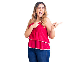 Young caucasian woman wearing casual clothes smiling and looking at the camera pointing with two hands and fingers to the side.