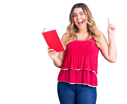 Young caucasian woman holding book surprised with an idea or question pointing finger with happy face, number one