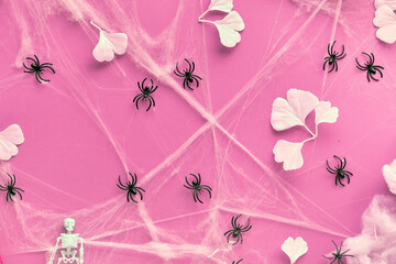 Creative Halloween background with white ginkgo leaves, spider web and black spiders on pink paper. Flat lay, top view, trendy background.