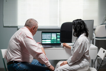 A man and a woman are looking at the x-ray on the monitor of the lap top.