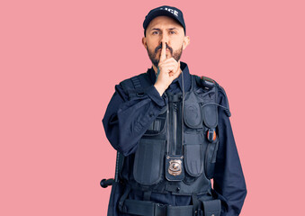 Young handsome man wearing police uniform asking to be quiet with finger on lips. silence and secret concept.