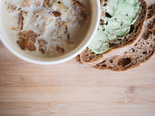 Creamy mushroom soup in cardboard cup served with bread with green color butter