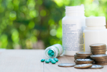 stack of coins with pills on the table in the nature blurred background