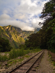 Fototapeta premium Amazing vertical landscape of mountain with sunrise colours from golden hour and blue sky with clouds and a trail rail in a hike trail travel near Machu Pichu, in Cusco, Peru