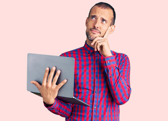 Young handsome man working using computer laptop serious face thinking about question with hand on...