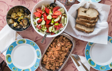Top view of a Greek lunch meal at summer with omellete, horiatiki salad, feta cheese and bread.