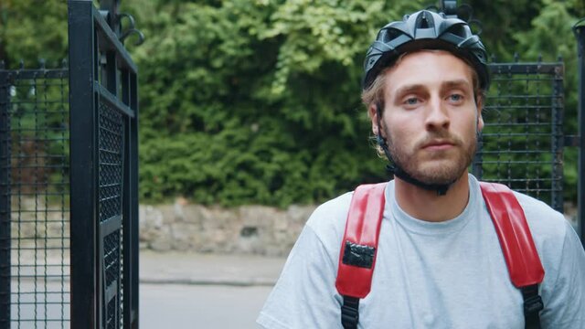 Attractive Tired Young Man Wearing Protective Helmet Coming Home Taking His Bicycle. Male Cyclist. Sport And Activities. Outdoors. Portrait.