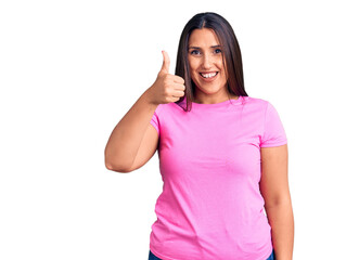 Obraz na płótnie Canvas Young beautiful brunette woman wearing casual t-shirt smiling happy and positive, thumb up doing excellent and approval sign