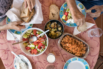 Top view of a Greek lunch meal at summer with omellete, horiatiki salad, feta cheese, grilled vegetables and bread.