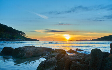 Fototapeta na wymiar Beautiful photo of a sunset on Chanteiro beach, with the rocks illuminated by the sun. Spain