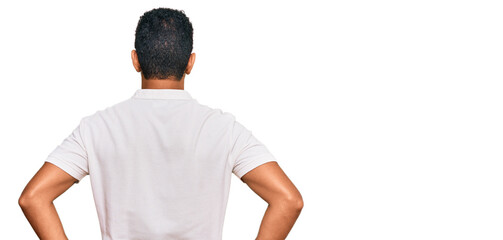Young arab man wearing casual clothes standing backwards looking away with arms on body