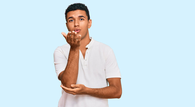 Young arab man wearing casual clothes looking at the camera blowing a kiss with hand on air being lovely and sexy. love expression.
