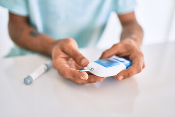 Young hispanic diabetic man measuring glucose level at home