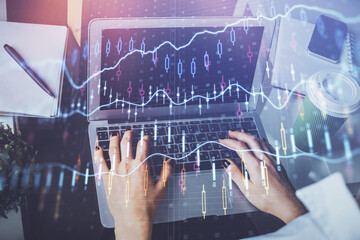 Double exposure of woman hands typing on computer and forex chart hologram drawing. Stock market...