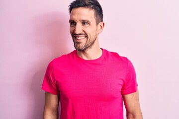 Obraz premium Young handsome man wearing casual t-shirt standing over isolated pink background looking to side, relax profile pose with natural face and confident smile.