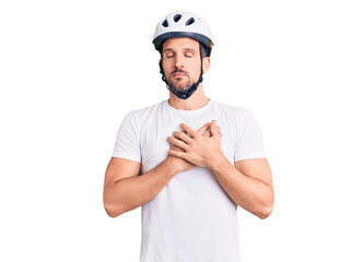 Young handsome man wearing bike helmet smiling with hands on chest with closed eyes and grateful gesture on face. health concept.