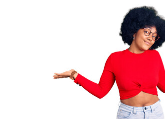 Young african american girl wearing casual clothes and glasses clueless and confused expression with arms and hands raised. doubt concept.