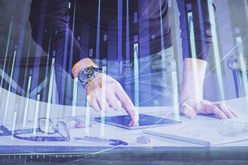 Double exposure of man's hands holding and using a digital device and forex graph drawing. Financial market concept.