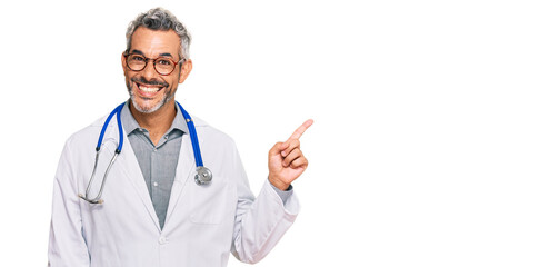 Middle age grey-haired man wearing doctor uniform and stethoscope smiling happy pointing with hand...