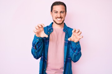Young handsome man wearing casual clothes smiling funny doing claw gesture as cat, aggressive and...