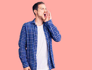 Young handsome caucasian man wearing casual clothes shouting and screaming loud to side with hand on mouth. communication concept.