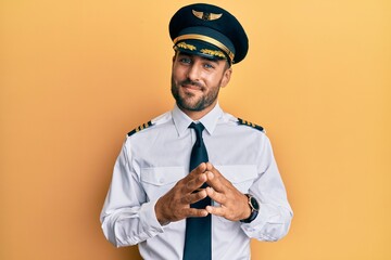 Handsome hispanic man wearing airplane pilot uniform hands together and fingers crossed smiling relaxed and cheerful. success and optimistic © Krakenimages.com