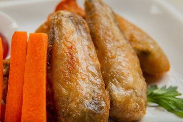 Fresh fried chicken wings on a white plate.