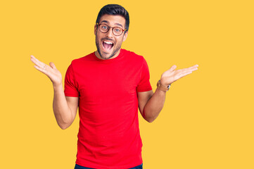 Young hispanic man wearing casual clothes and glasses celebrating victory with happy smile and...