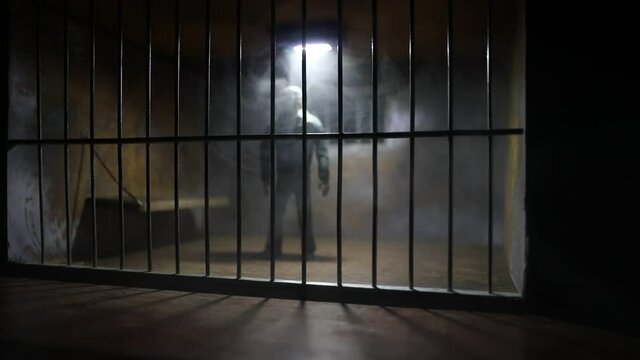 Man in prison man behind bars concept. Old dirty grunge prison miniature. Dark prison interior creative decoration with handcuffs. Selective focus