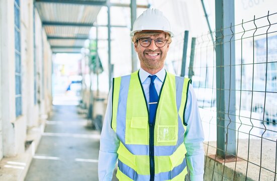 Business architect man wearing hardhat standing outdoors of a building project wearing reflective vest