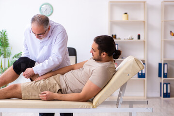 Experienced doctor traumatologist examining young male patient