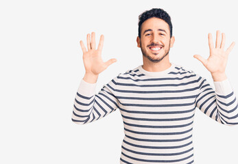 Young hispanic man wearing casual clothes showing and pointing up with fingers number ten while smiling confident and happy.