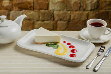 Fresh cheesecake on a white plate with jam in a restaurant.