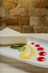 Fresh cheesecake on a white plate with jam in a restaurant.