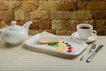 Fresh cheesecake on a white plate with jam in a restaurant.