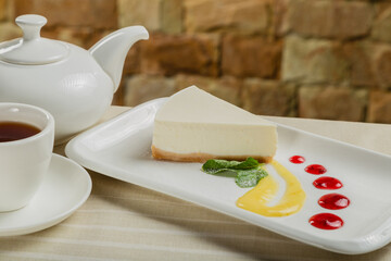 Fresh cheesecake on a white plate with jam in a restaurant.