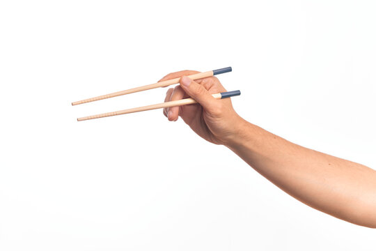 Hand of caucasian young man holding chopsticks over isolated white background