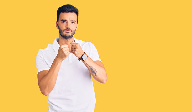 Young handsome hispanic man wearing casual clothes ready to fight with fist defense gesture, angry and upset face, afraid of problem