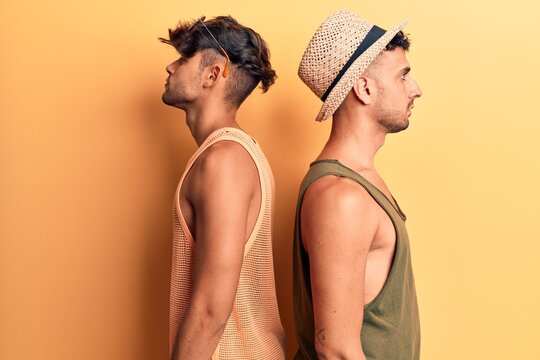 Young gay couple wearing summer clothes looking to side, relax profile pose with natural face with confident smile.