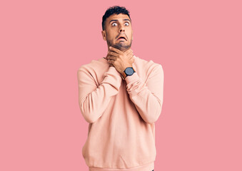 Young hispanic man wearing casual clothes shouting suffocate because painful strangle. health problem. asphyxiate and suicide concept.
