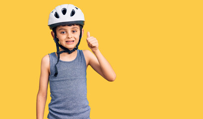 Little cute boy kid wearing bike helmet smiling happy and positive, thumb up doing excellent and approval sign