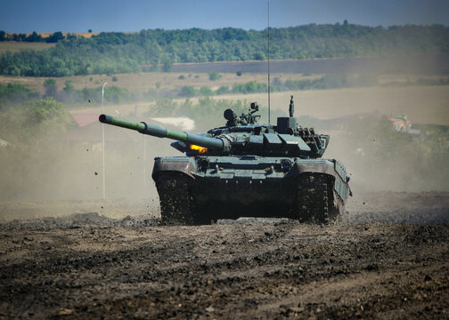 Russian battle tank T-72B3 moving on the training ground and firing from a machine gun