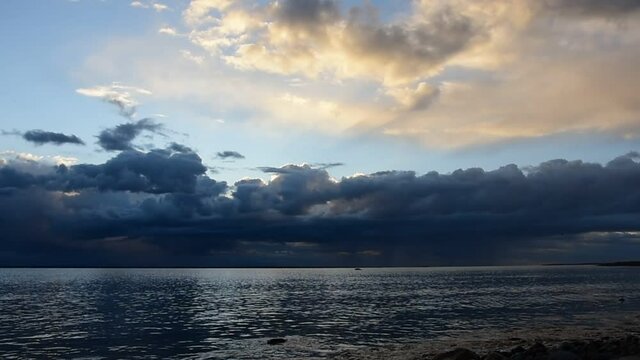 The sea after a storm over the Swedish Baltic Sea at sunset where the sun's rays light up between the clouds and the sky starts to turn blue again late at night