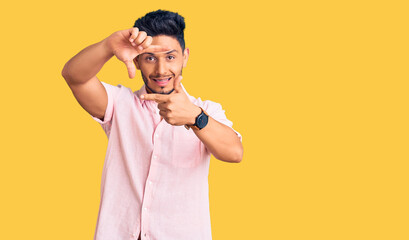 Handsome latin american young man wearing casual summer shirt smiling making frame with hands and fingers with happy face. creativity and photography concept.