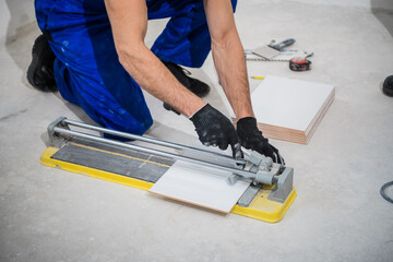 The builder measures the tiles and cuts them with a ceramic saw
