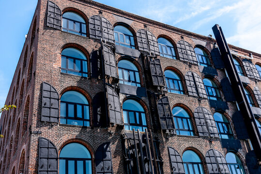 19th Century brick warehouse in Red Hook, Brooklyn, NYC, with arched windows and metal shutters, has been renovated into residential loft apartments.