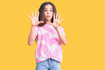 Cute hispanic child girl wearing casual clothes afraid and terrified with fear expression stop gesture with hands, shouting in shock. panic concept.